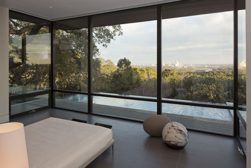 This bedroom with floor-to-ceiling windows, enjoys the views of downtown Austin and the pool outside.