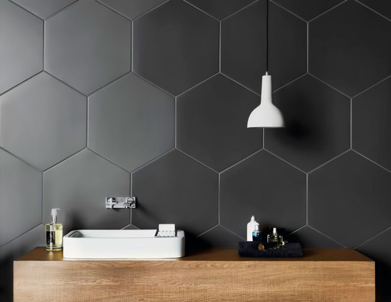 Bathroom Tile Ideas - Grey Hexagon Tiles // Large hexagonal charcoal tiles on the walls of this bathroom create a unique, modern look that compliments the wood countertop and contrasts the white sink and light fixture.