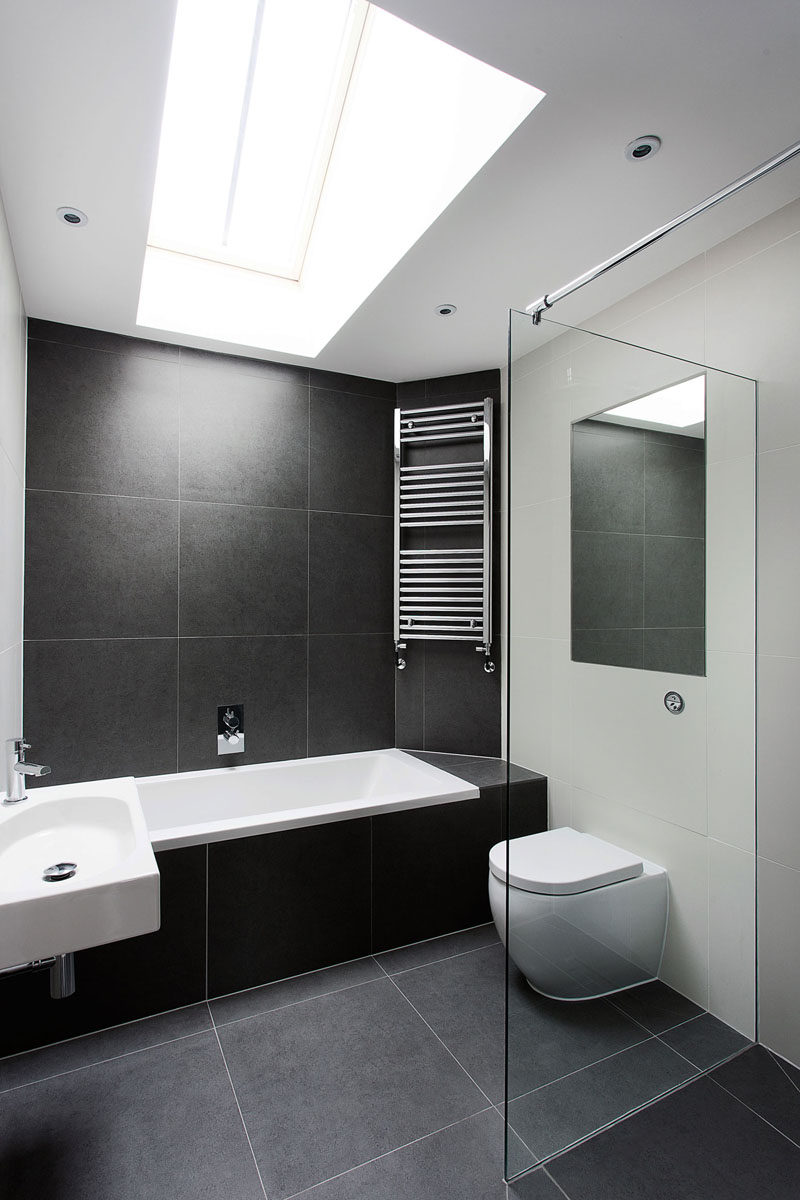 Bathroom Tile Ideas - Use Large Tiles On The Floor And Walls // The large black stone tiles in this bathroom help to create a simple black and white color scheme, and the light from the skylight makes the bathroom feel taller and more open.