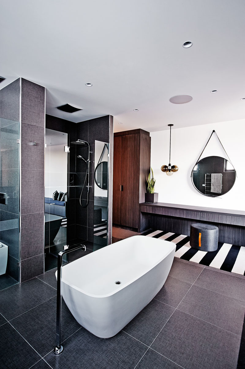 Bathroom Tile Ideas - Use Large Tiles On The Floor And Walls // The texture of the large dark tiles on both the floor and walls of this bathroom work well with the texture of the vanity and wardrobe, also found in the bathroom.