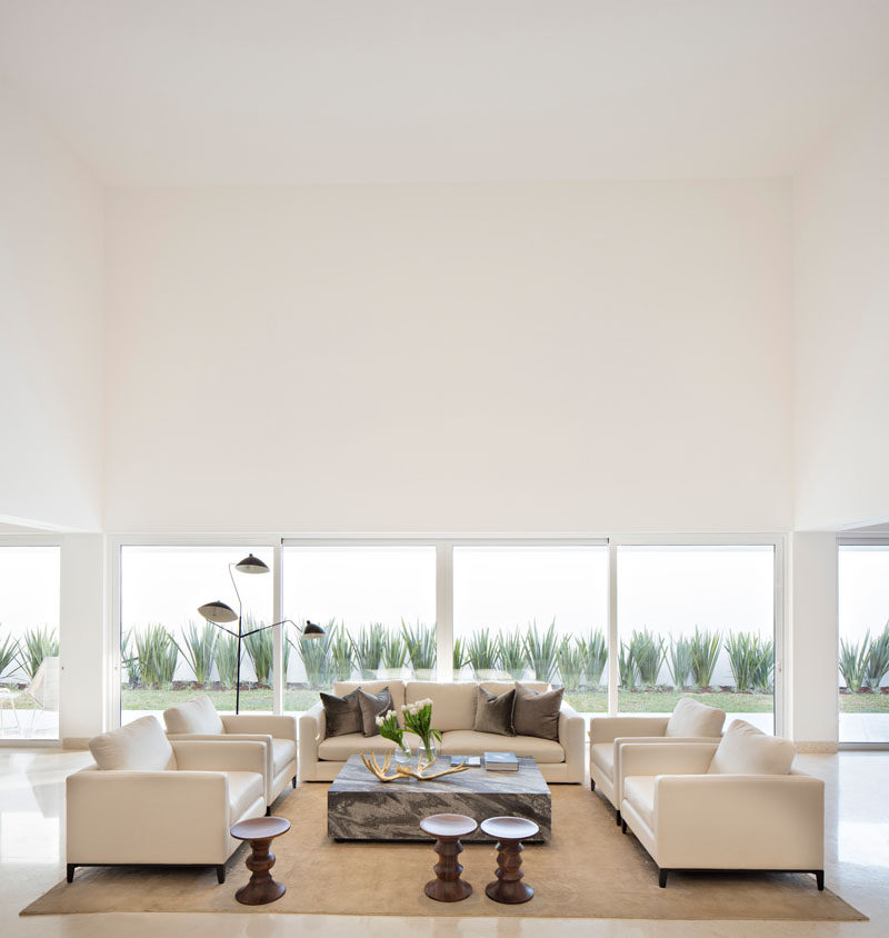 This sitting area has a double height ceiling that becomes the center of the home, and has views of the landscaped backyard.