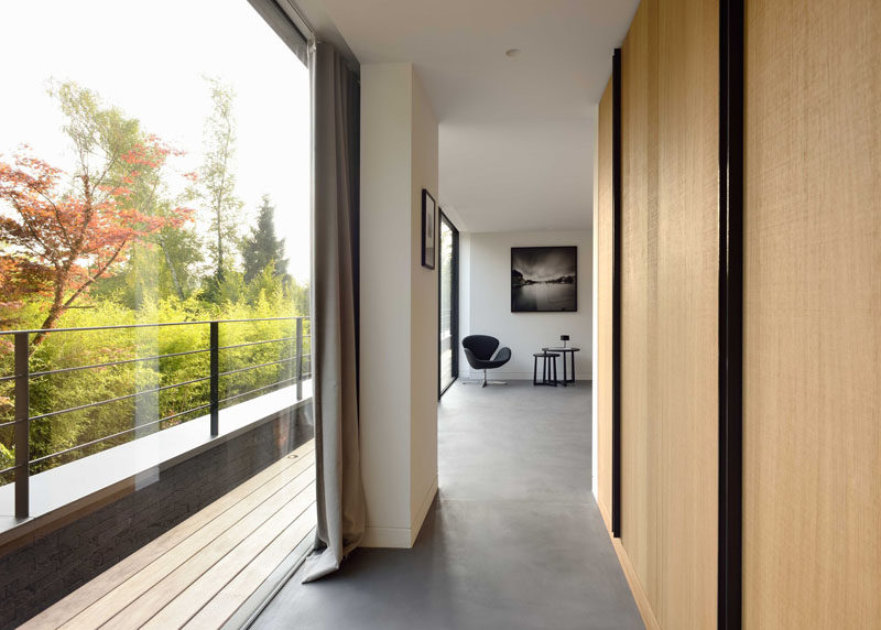 This master bedroom is tucked away down a hallway that has large floor-to-ceiling windows.