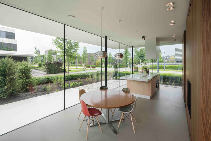 Inside this modern home, light ceilings and floors reflect the light, and a wall of wooden cabinetry provides storage for the combined kitchen and dining room.