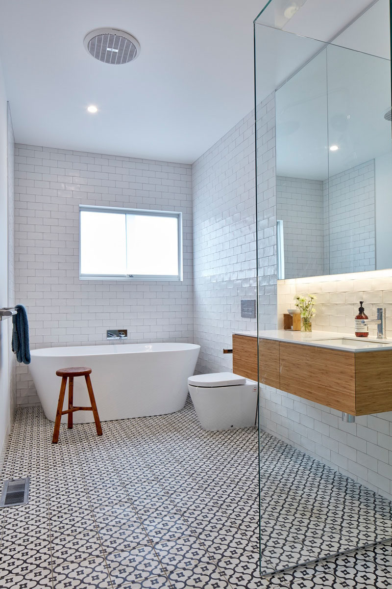 This bathroom features white subway tiles that cover the walls, and a decorative tile has been used on the floor.
