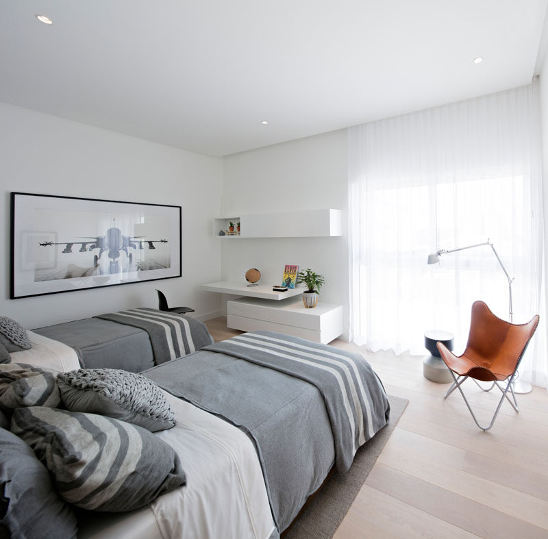 In this bedroom, darker grays, a black and white photo, and a bold leather chair help to create a masculine look.