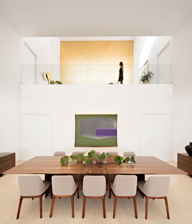 This dining room has a double height ceiling and views of a large gold wall that's located upstairs.