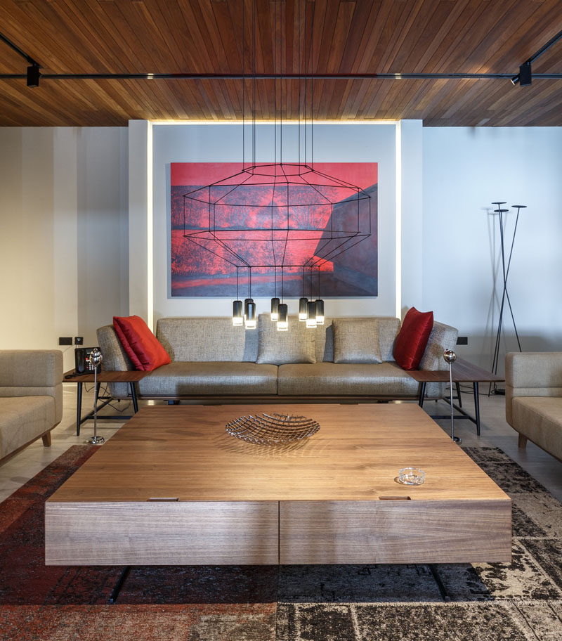 This formal lounge room has a minimal line chandelier, with bold red artwork and cushions adding a touch of color. #LoungeRoom #LivingRoom