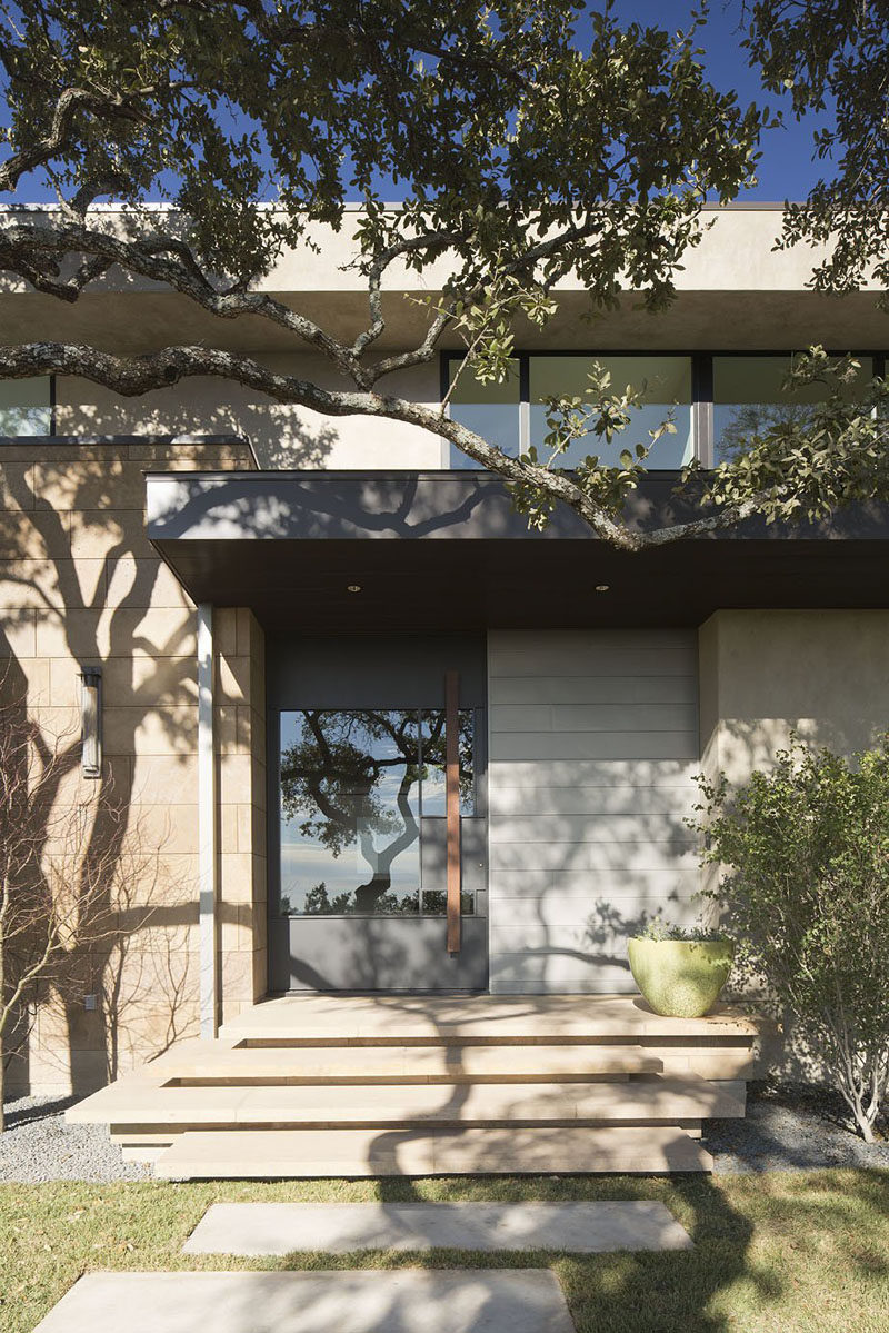 A stone path leads to stone steps and the large modern front door of this home.