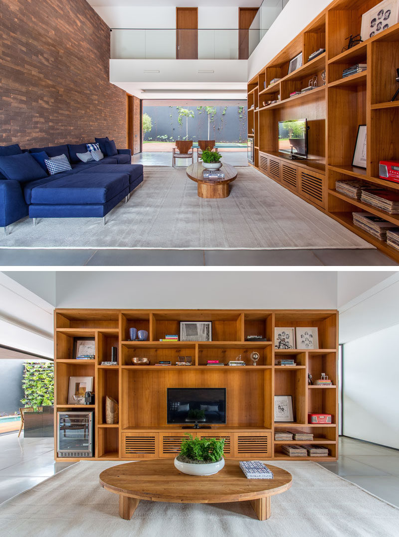 In this living room a large wooden shelving unit fills the space perfectly, and on the opposite wall, bricks have been used as a feature wall behind the sofa.