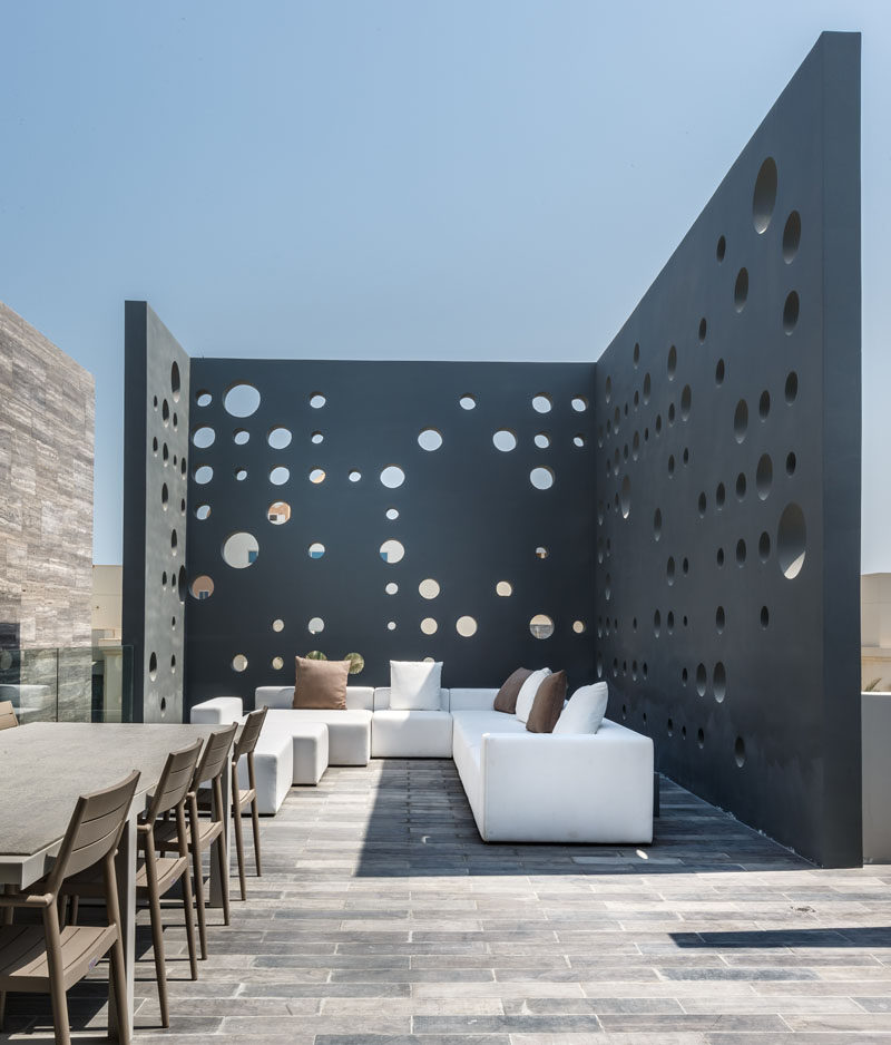 This home has a rooftop deck with lounge and outdoor dining area that's surrounded by perforated walls for privacy. #RooftopDeck #Screen #OutdoorScreen #Landscaping #LandscapeDesign