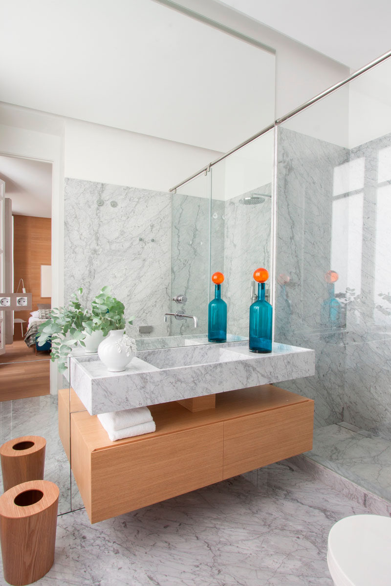 Bathroom Design Ideas - Open Shelf Below The Countertop // The wood used on the shelf in this bathroom is the same wood used on the walls and floor of the bedroom, creating a cohesive look and helping to warm up the marble used throughout the rest of the bathroom.