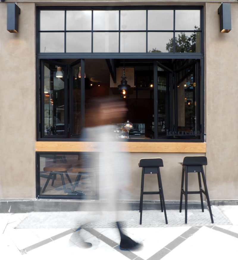 This cafe has a serving window that allows people to sit outside at a wooden bar.