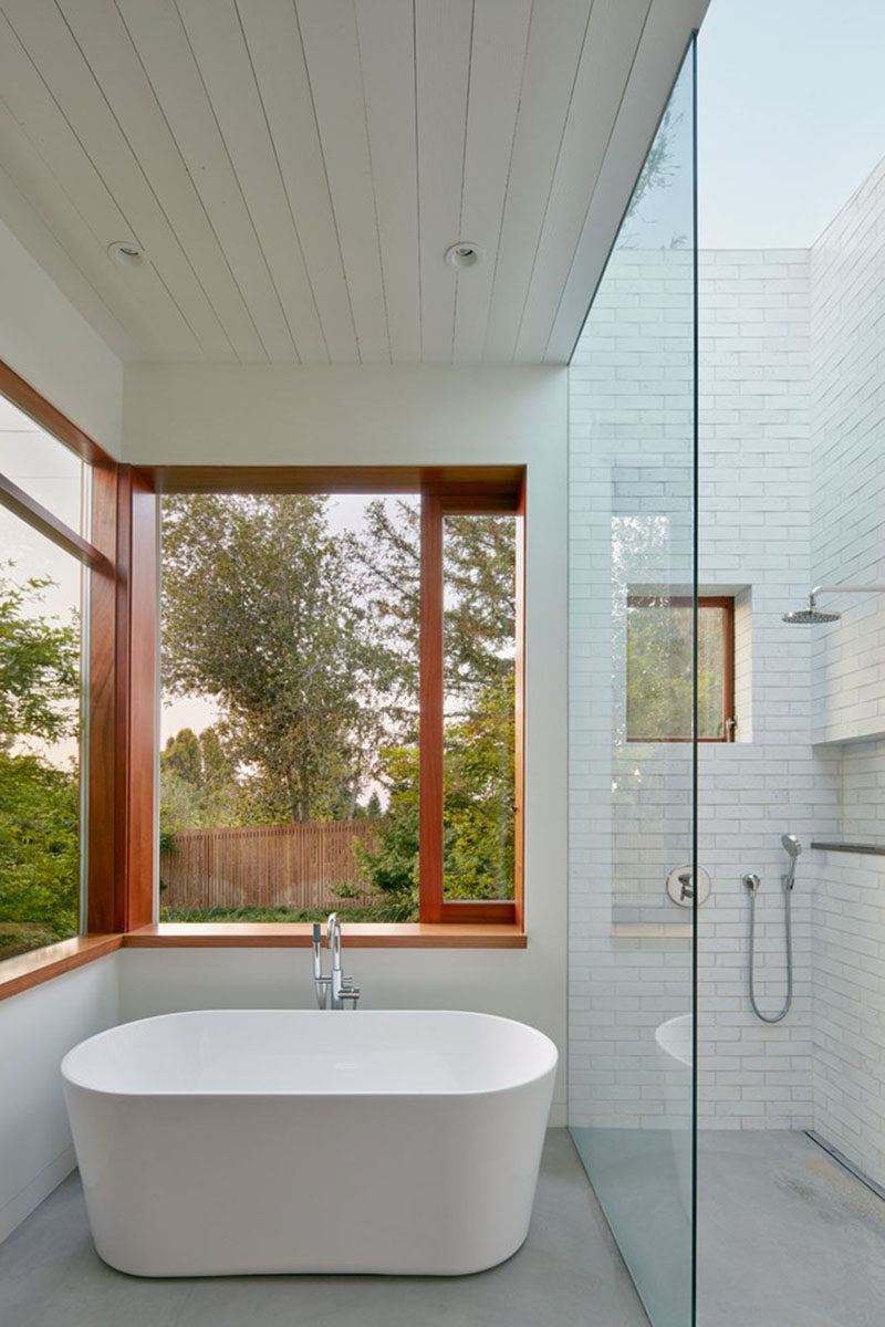 This master bathroom has a glass enclosed shower with skylight, and a deep soaker tub with views of the surrounding nature.