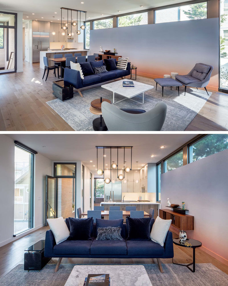 Inside this modern beach house, the main living, dining and kitchen are all located in the same room, with a custom accent wall featuring a calming wallpaper installation by Calico Wallpaper.