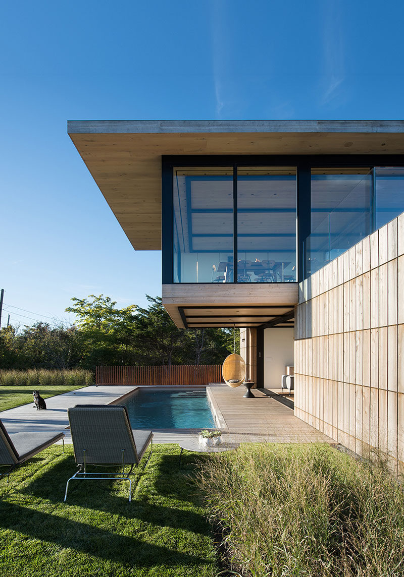 A swinging chair hangs from the cantilevered section of this modern house and a provides a place to relax by the pool.