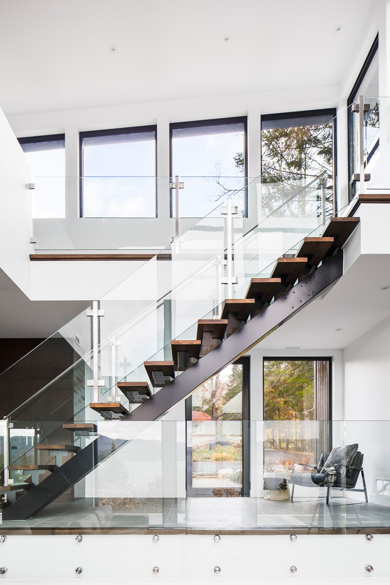 Wood and steel stairs with glass safety railings guide to you the upper level of this modern lakeside home.