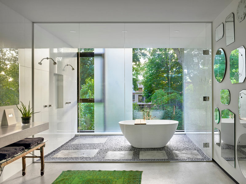 In this bright bathroom, a sliding frosted glass privacy panel can be used when needed, and vintage mirrors collected by the home owner cover the wall.