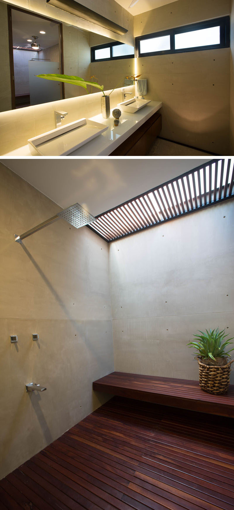 In this bathroom there's a vanity with double sinks and a shower that has a wooden floor, a skylight and built-in bench.