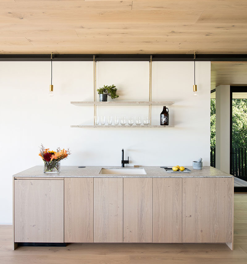 This small bar area with hardware-free cabinetry has hanging shelves create a unique place to display glassware.