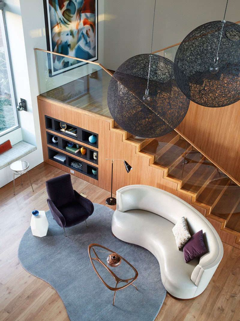 Interior Design Ideas - 17 Modern Living Rooms As Seen From Above | Soft curves on the rug, coffee table, armchair, and couch give this living room area a relaxing feel that compliments the clean lines of the stairs and built in shelving.