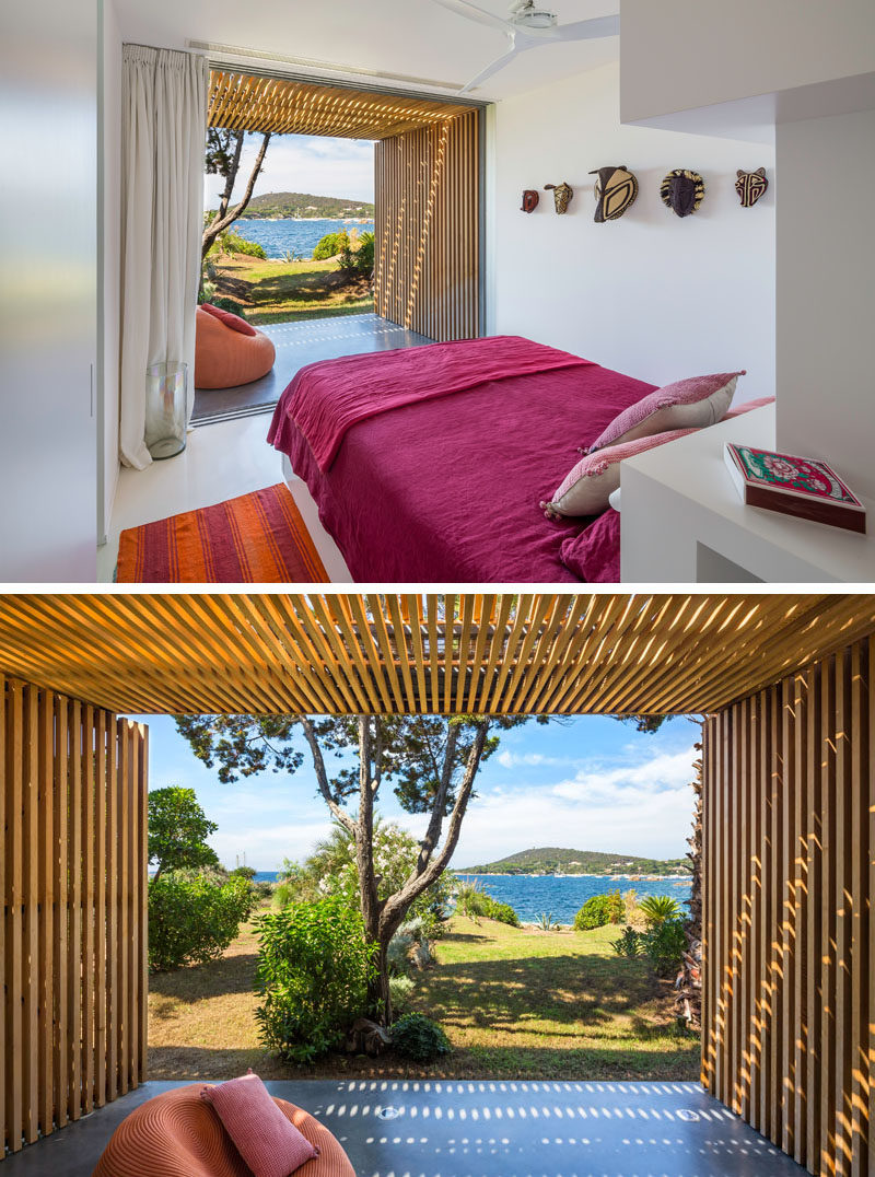 This pink and white bedroom has its own covered patio area. Wooden masks on the wall create a simple art installation.