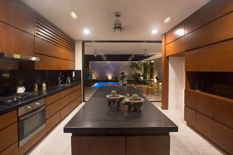 This mostly wood kitchen with black countertops opens up to a courtyard with small swimming pool.