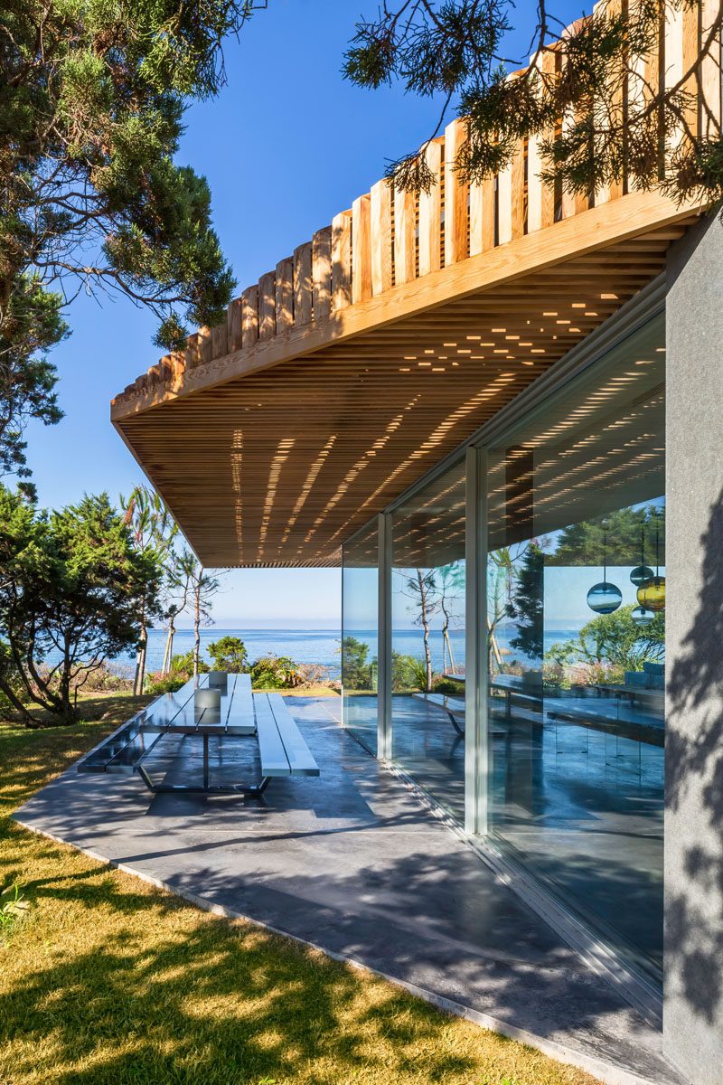 Off to the side of the dining area and kitchen in this modern villa, is an outdoor dining area set up with a large picnic style table with benches.