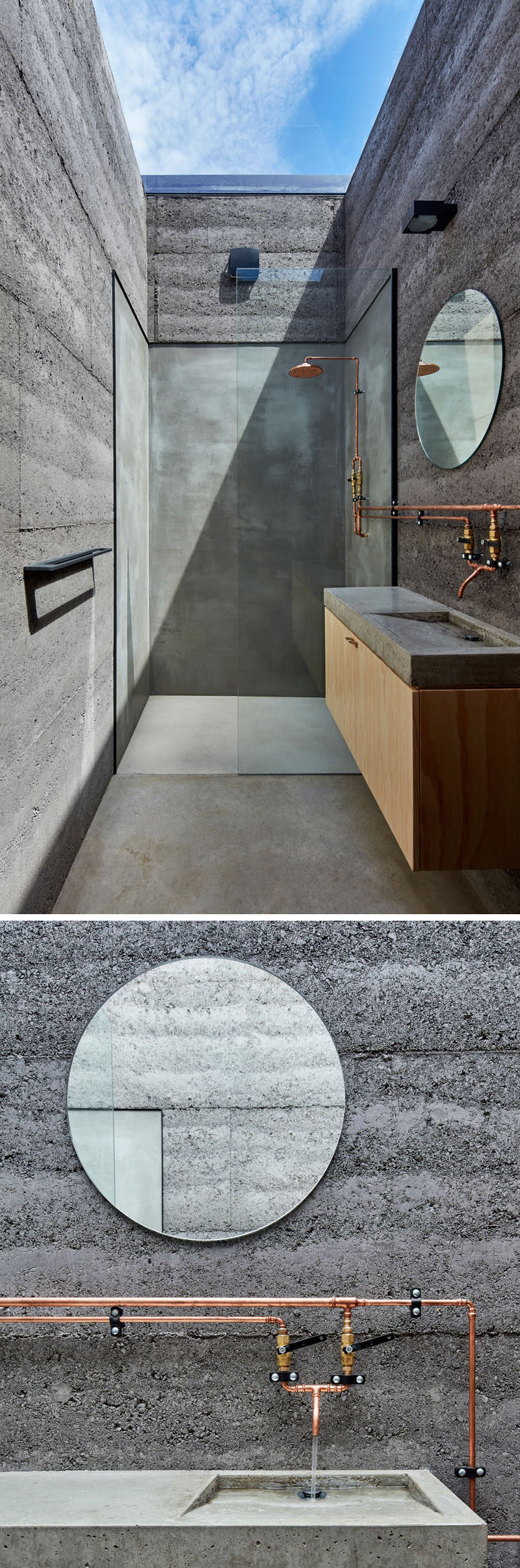 The bathroom has walls made from rammed earth in a charcoal color., and a large skylight makes it appear as though you are showering outdoors.