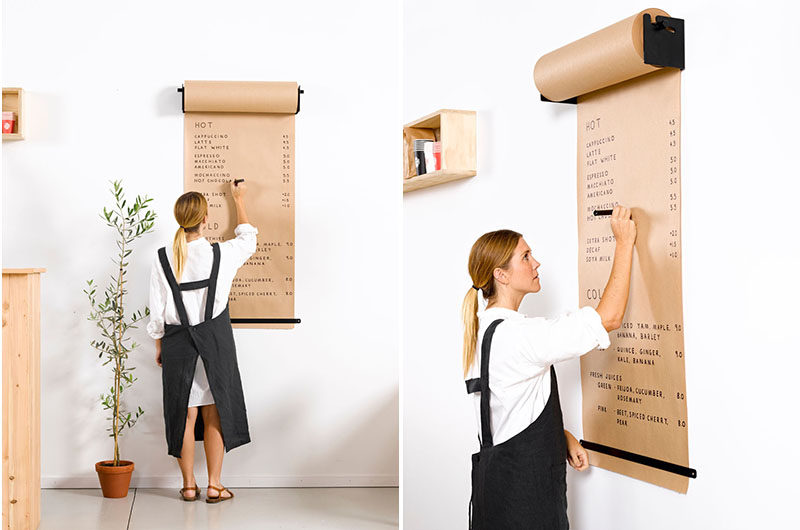 A woman writes on brown craft paper rolled from a large wall-mounter paper roll. 