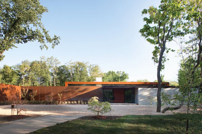 15 Single Story Modern Houses | The exterior of this single story house is clad in steel that creates harsh lines but that are softened by the trees surrounding it.