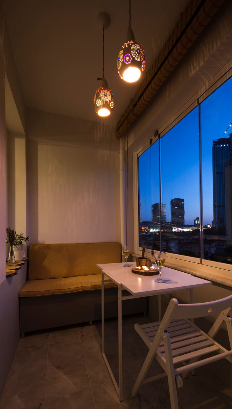 This small enclosed balcony has small built-in banquette and a set of decorative pendant lights help to create a relaxing atmosphere.