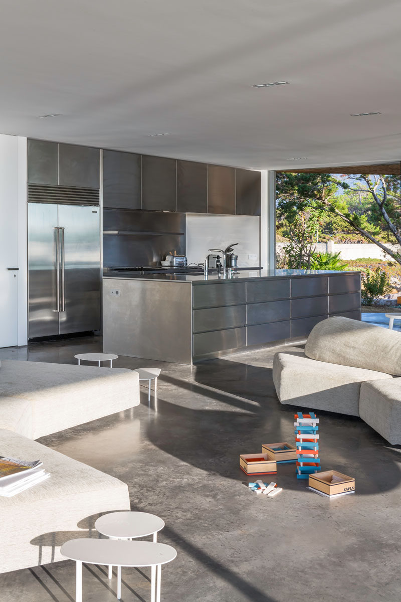 Sharing the open floor plan of the living and dining room in this modern villa is the kitchen. Concrete flooring and stainless steel cabinetry has been used to create more of an industrial looking space.