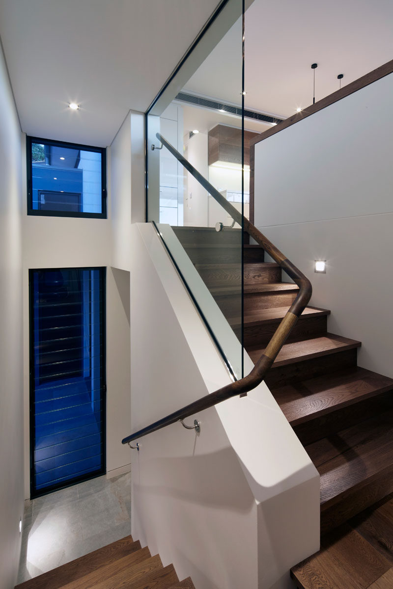 Inside this modern townhouse, white walls and wood feature throughout the interior, like in this staircase with a curved wooden handrail.