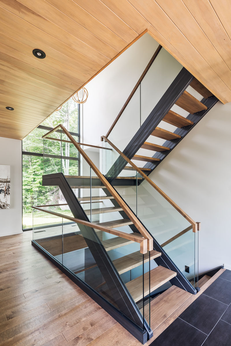 Stepping inside this contemporary home, you are greeted by a staircase that's filled with natural light from the large windows overlooking the backyard.