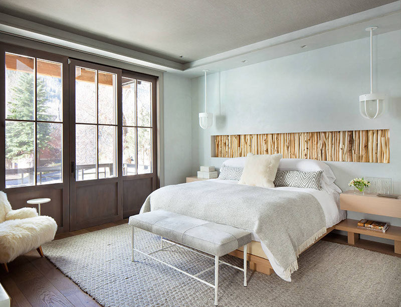 This bedroom has a recessed wall section filled with rustic branches that act as a headboard above the bed