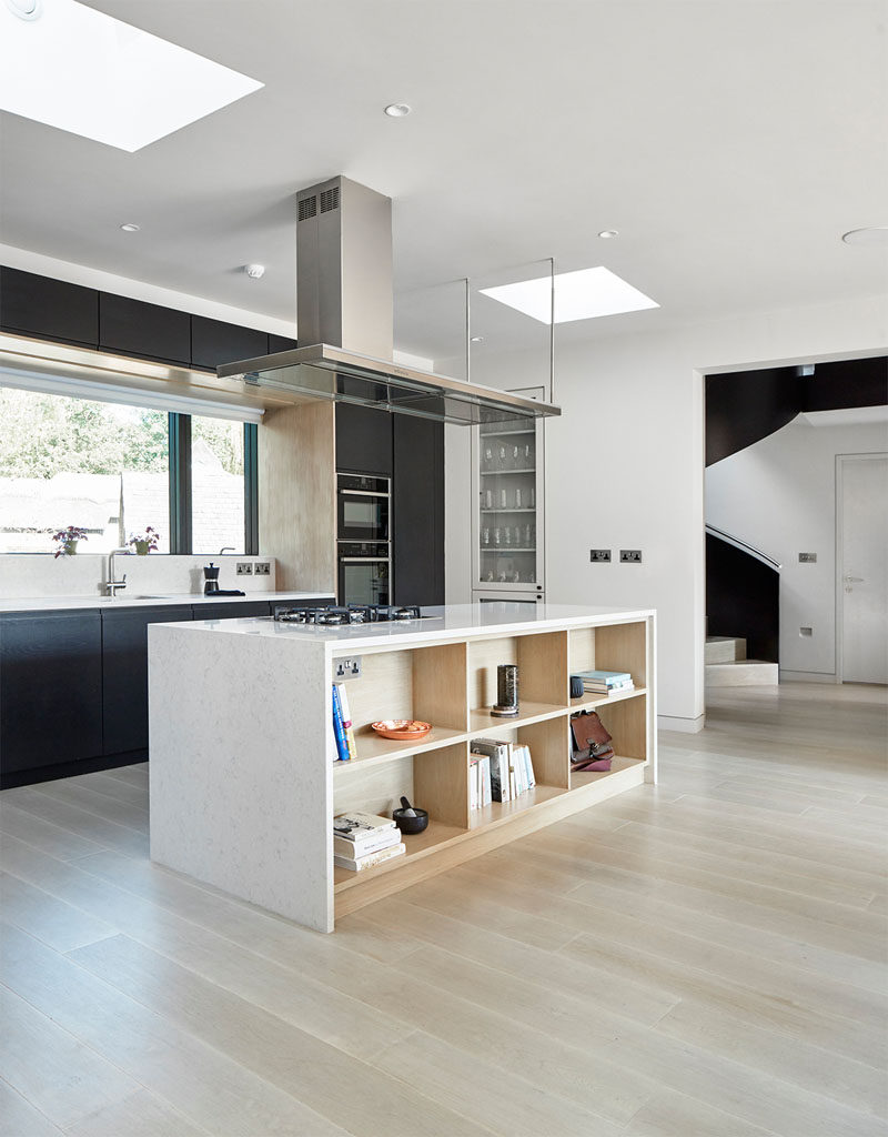 This modern kitchen has matte black cabinets and a large island with built-in open shelving.