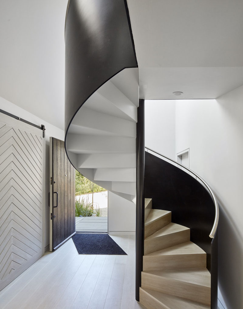 This modern entry hallway is home to a black, white and wood spiral staircase.