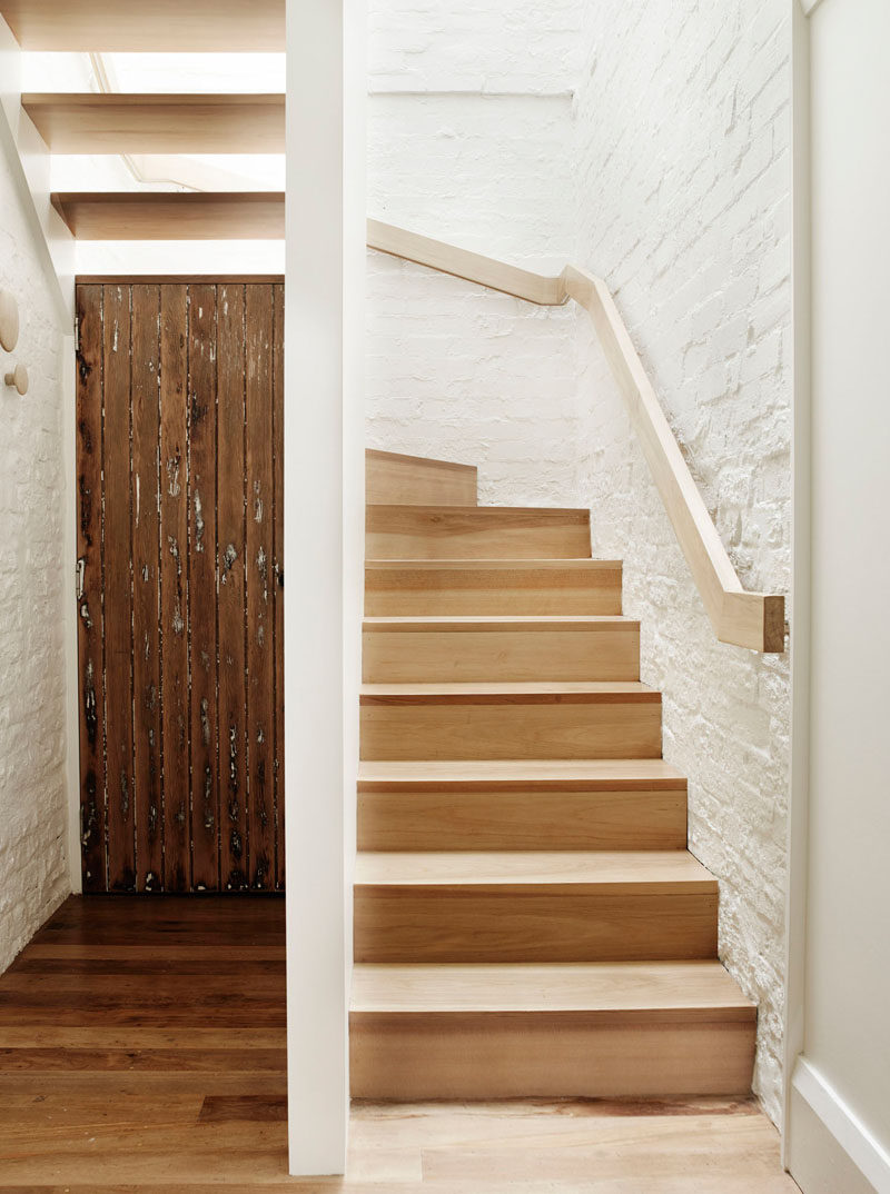 Simple light wood stairs and handrail as well as white painted brick lead you up to the second floor of this renovated home.