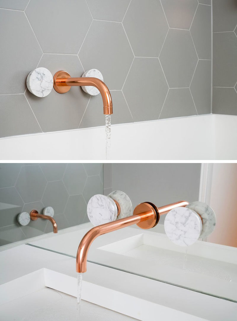 This bathroom features copper and marble fixtures next to light gray hexagon tiles