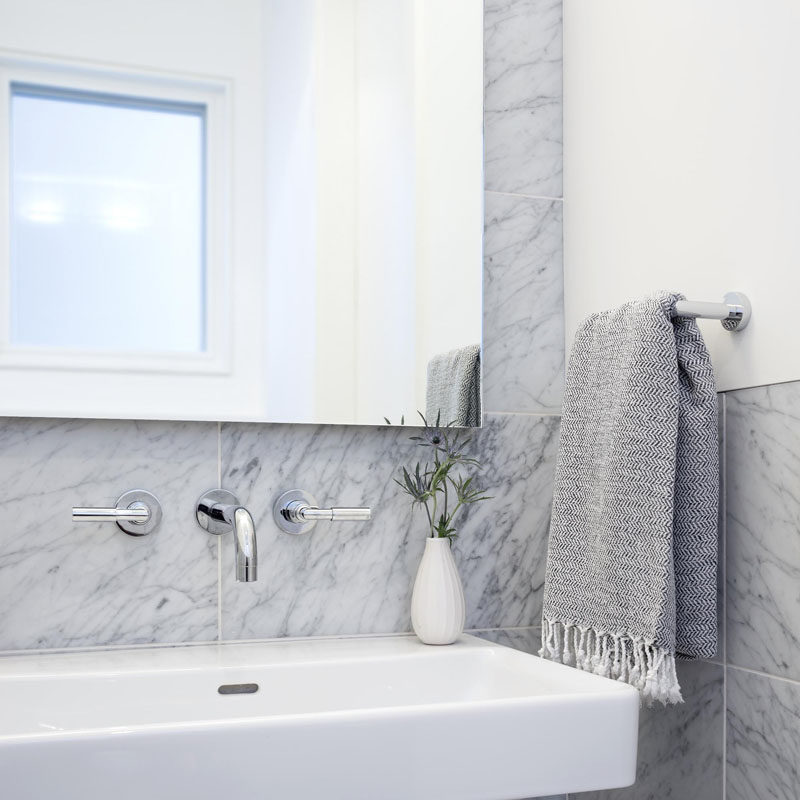 A simple palette of white Carrara marble with a white vanity has been used in this modern bathroom.