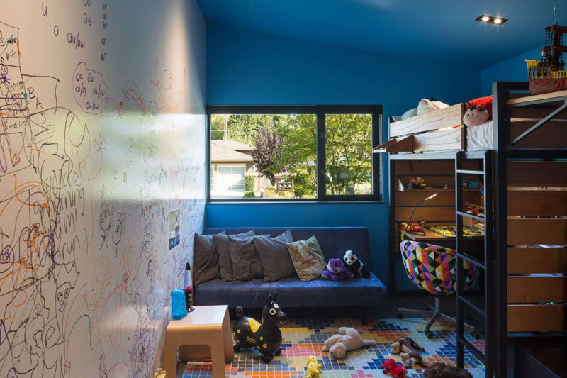 A dry erase wall, bold blue walls and a raised bed with a desk underneath make this kids room fun and playful.