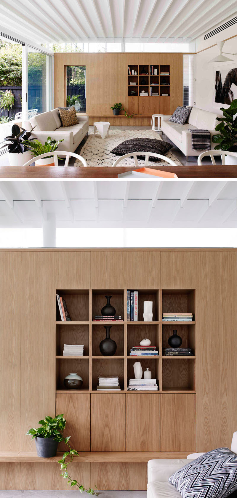 Large sliding glass doors open up this living room the backyard, and a wooden accent wall breaks up the light interior palette. Built-in storage in the wooden wall creates a space to display personal items.