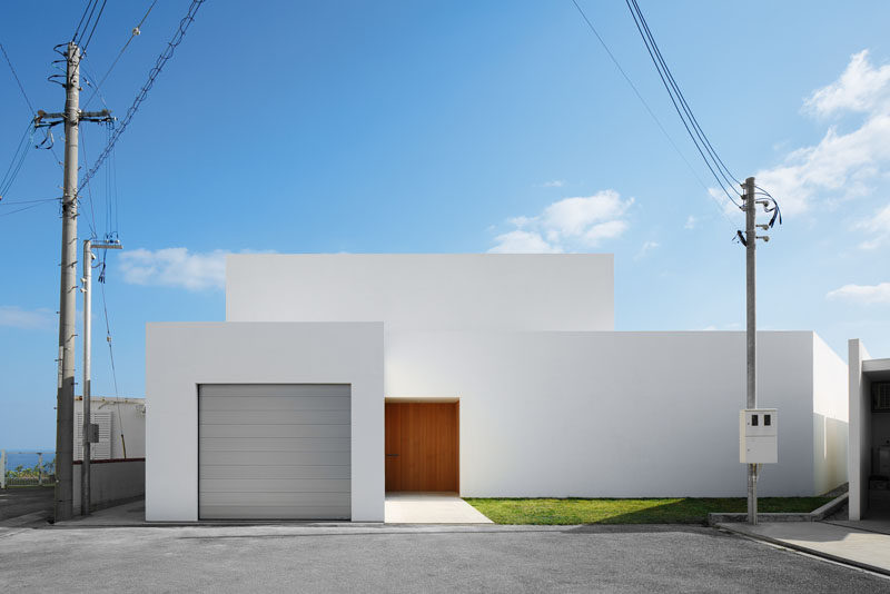 12 Minimalist Modern House Exteriors // This simple white minimalist house features a grey garage door and a wooden front door to give the house a modern look and warm up the all white exterior.