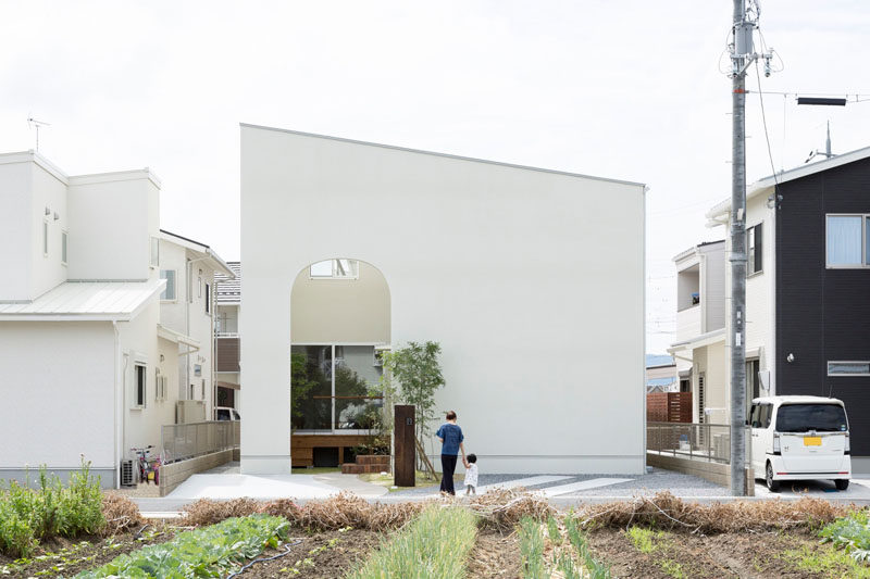 12 Minimalist Modern House Exteriors // An all white exterior wall provides privacy for the home and makes the exterior of the house look simple and modern with the angled roof and arched entrance.