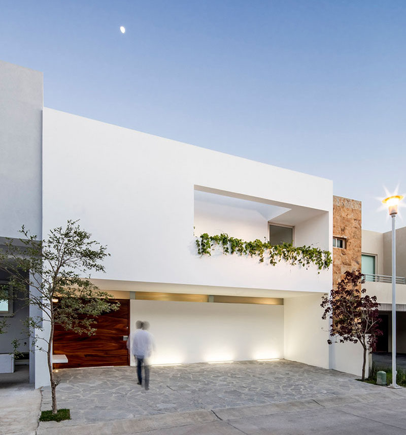 12 Minimalist Modern House Exteriors // The oversized wood door and dripping greenery on the front of this house warm up the white and make the minimalist exterior more inviting.