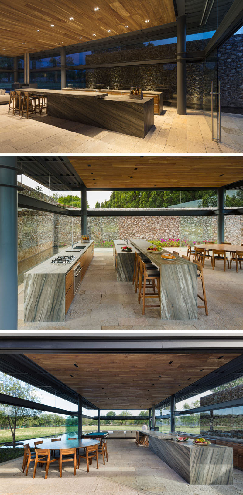 Inside this contemporary visitors pavilion there's a kitchen to the right with an oversized island covered in stone, and on the left is a round wooden dining table. 