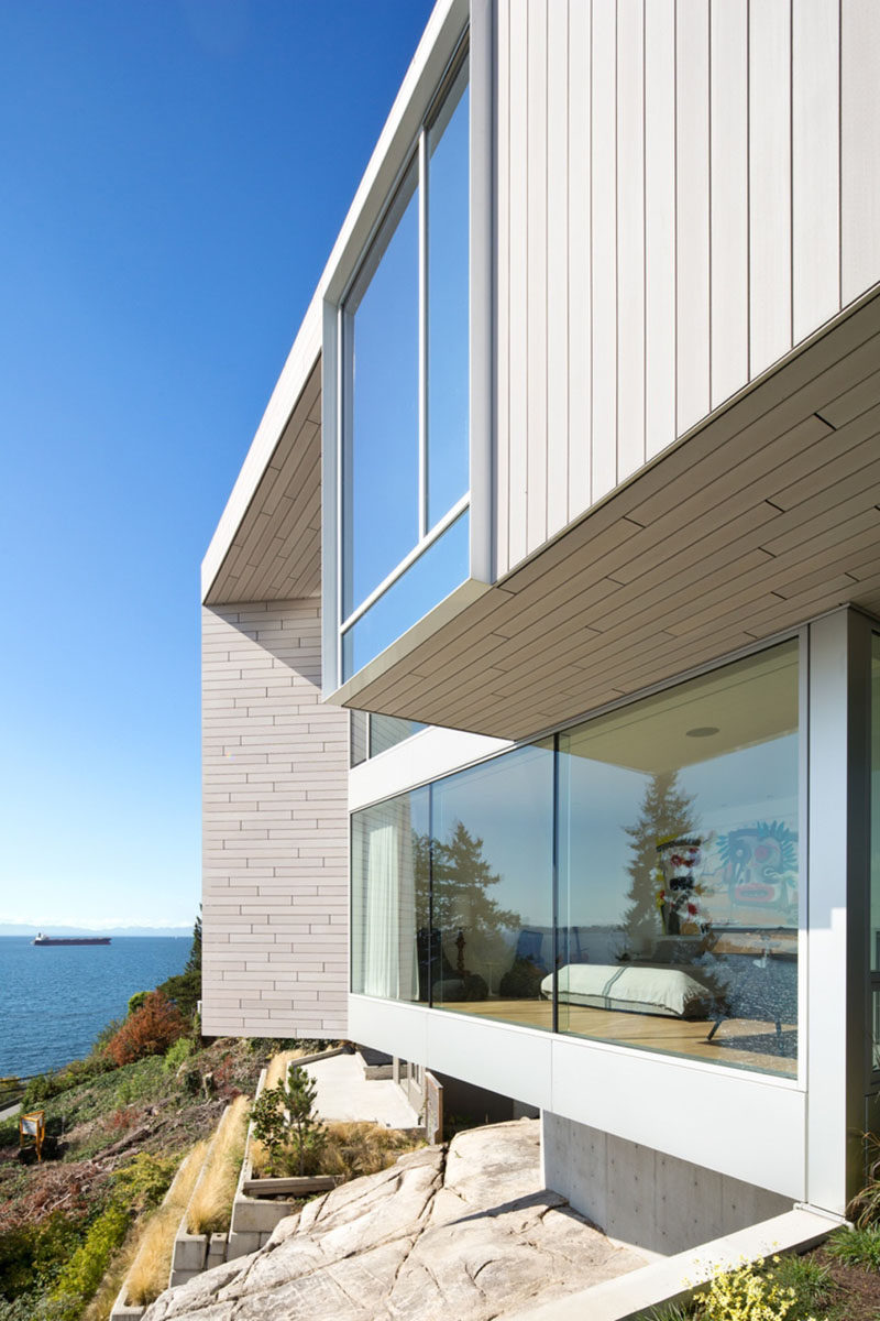 This concrete and wood modern house with light wood siding, has large windows to enjoy the ocean view.