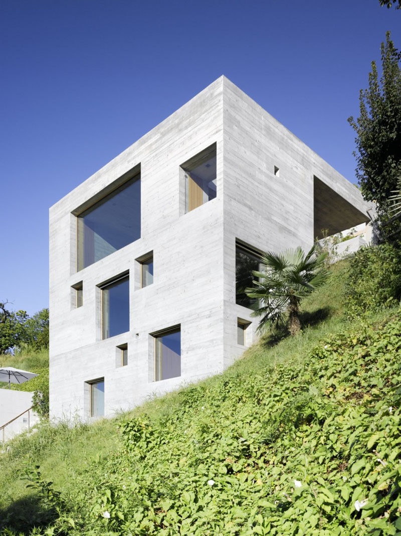 13 Modern House Exteriors Made From Concrete | Square cutouts for the windows on the exterior of this concrete house create a patterned look that's accentuated at night when light shines through the windows.