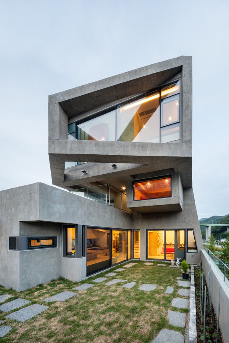 13 Modern House Exteriors Made From Concrete | Smooth concrete has been used for the exterior of this home and and is brightened by the warm light that shines through the windows.