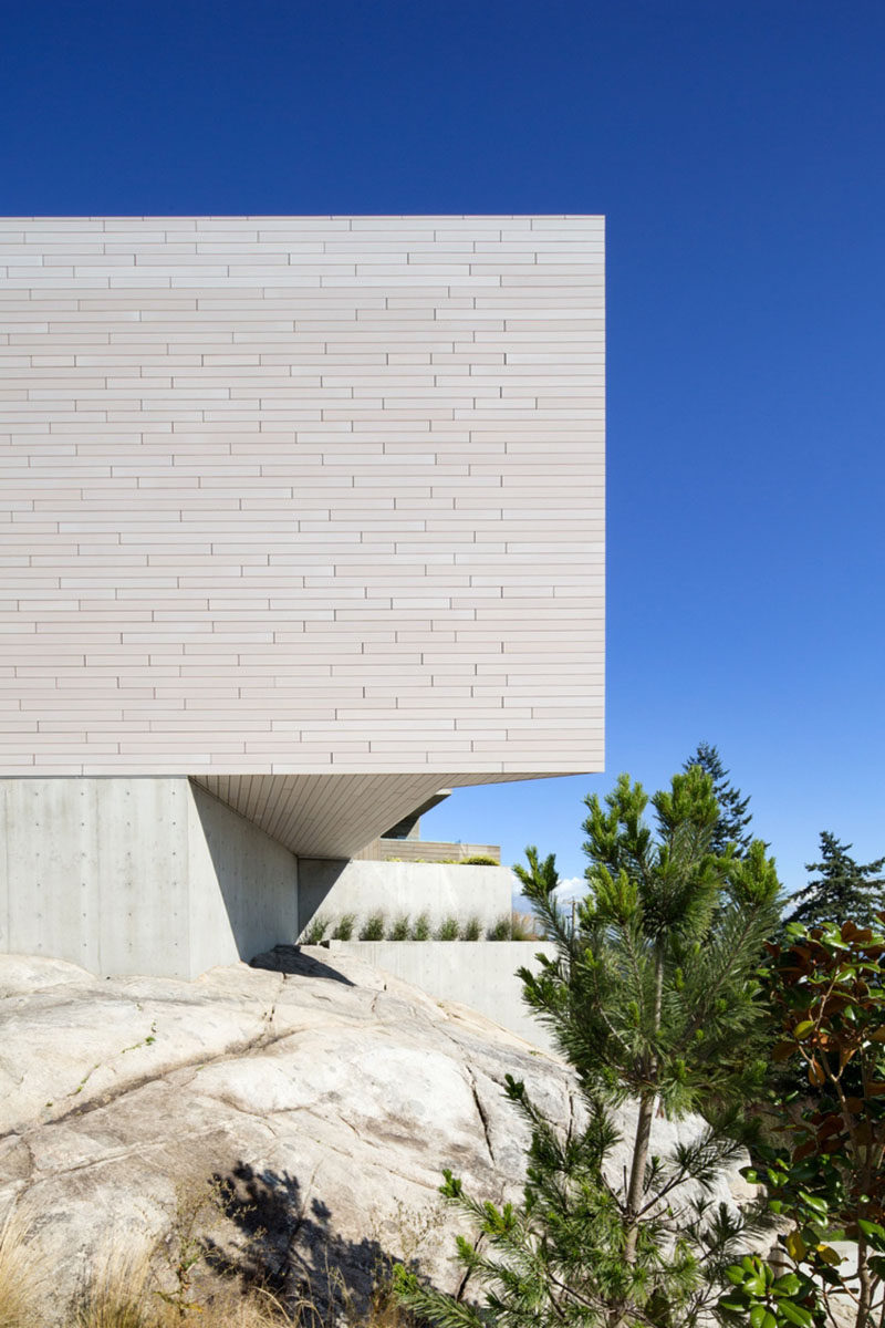 This modern house has a concrete foundation, while the wood siding overhangs it to create an angular and dramatic appearance.